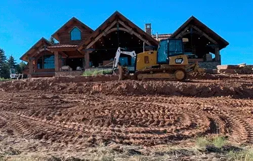 Construction site with a house under construction and a bulldozer on muddy ground