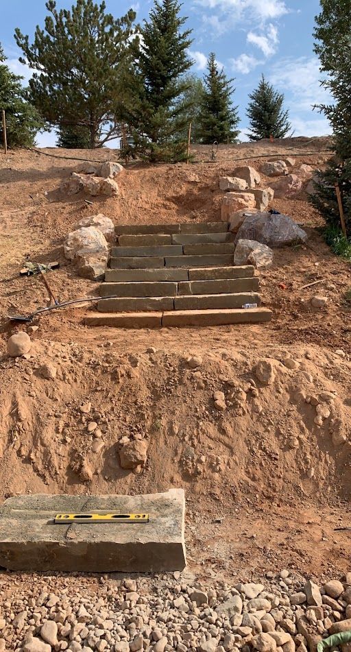 Stone steps cut into a dirt slope with trees above and a measuring tool at the bottom.