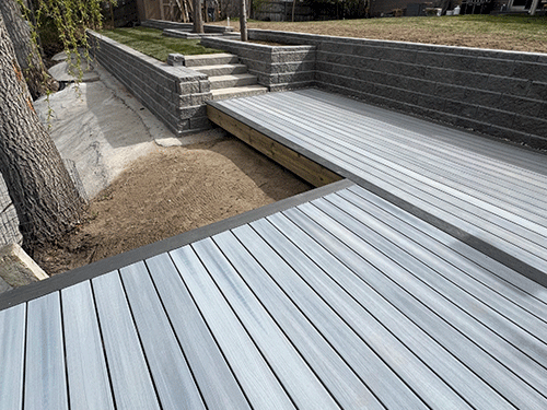 Long gray wooden boardwalk over a dry landscaped channel with stone retaining walls