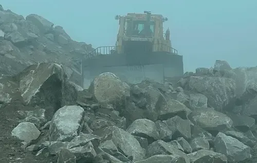 Bulldozer working on a rocky construction site in heavy mist