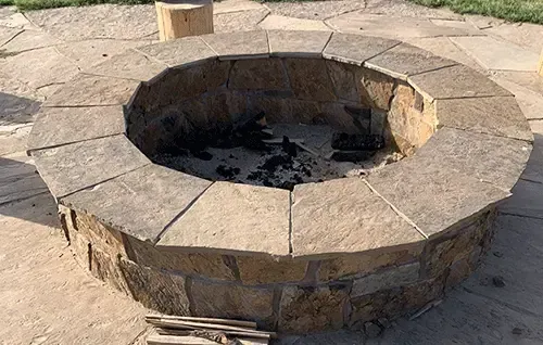 Stone fire pit with a circular bench in a paved outdoor area