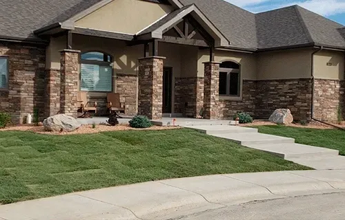 Suburban house with stone facade, front lawn, walkway, and driveway near the curb