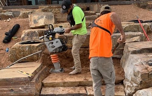 Workers operating a stone-cutting machine on a rocky construction site