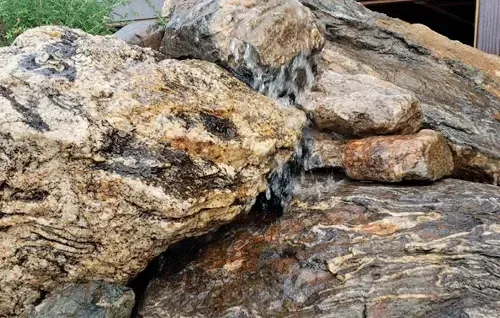 Large tan and gray rocks with a small stream of water trickling through them