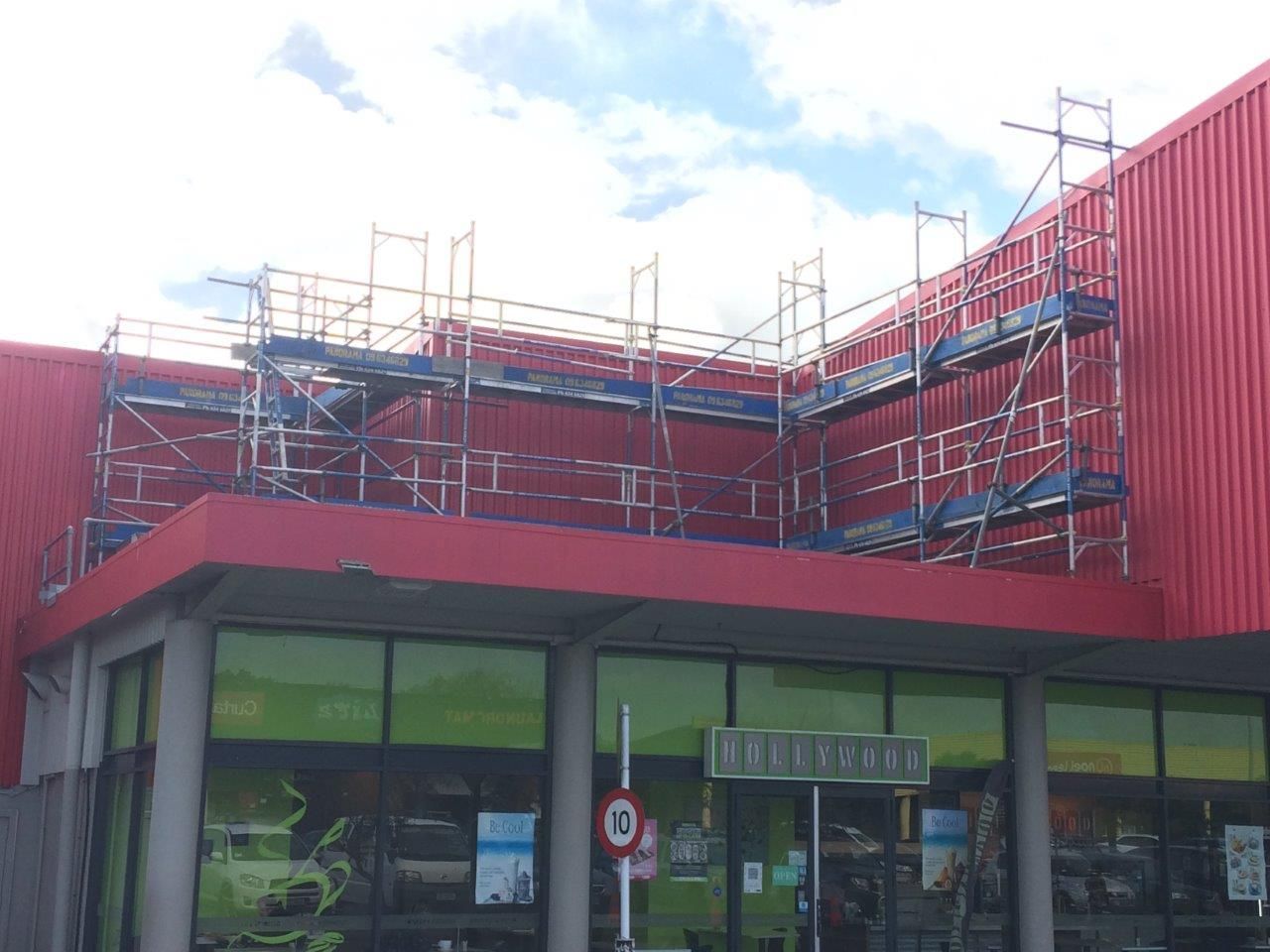 Red building under construction with scaffolding above a storefront entrance