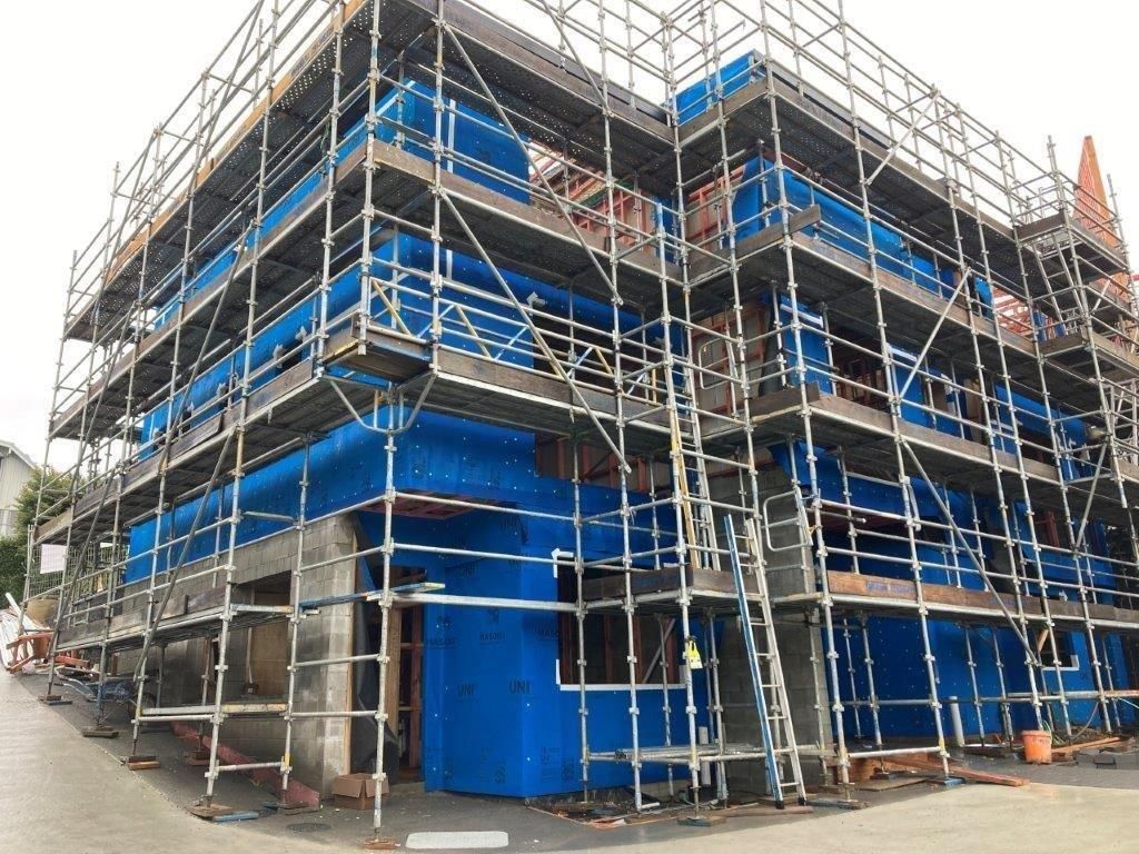 Blue-covered construction scaffolding around a building under renovation