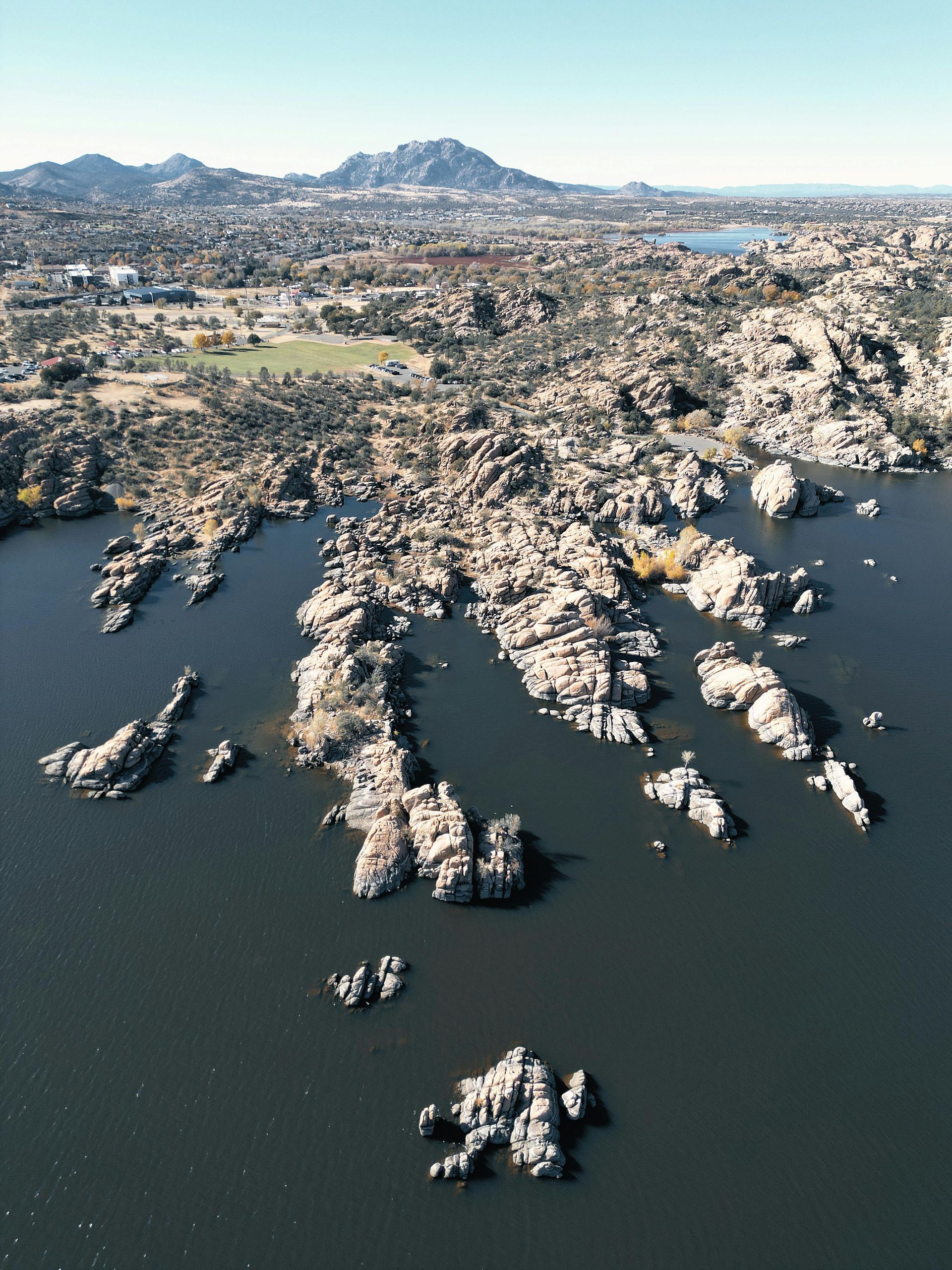 Aerial view of rocky islands and dark blue water with mountains in the distance.