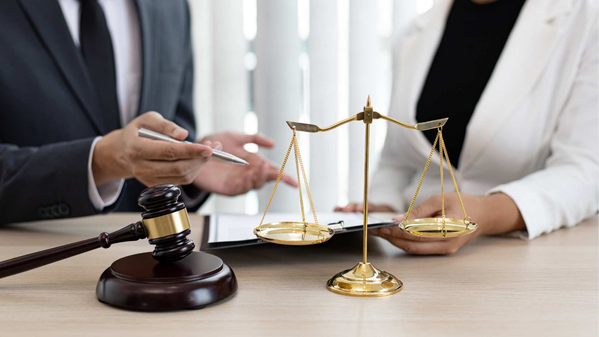 Lawyer’s desk with gavel, balance scales, and two people discussing a legal case