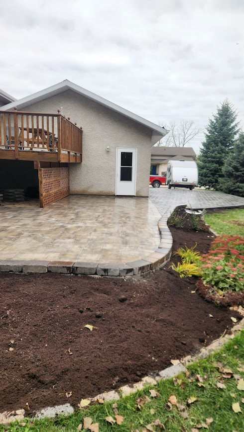 Stone patio with deck and flowerbed