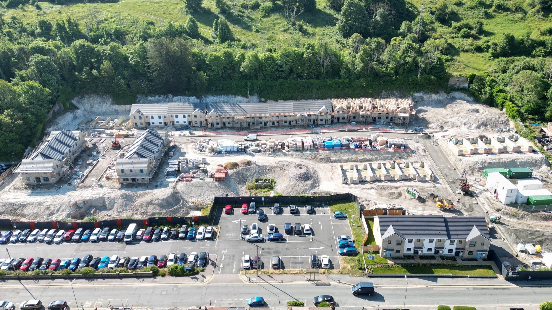 Aerial view of a construction site with multiple buildings in various stages of completion; parking lot in front.