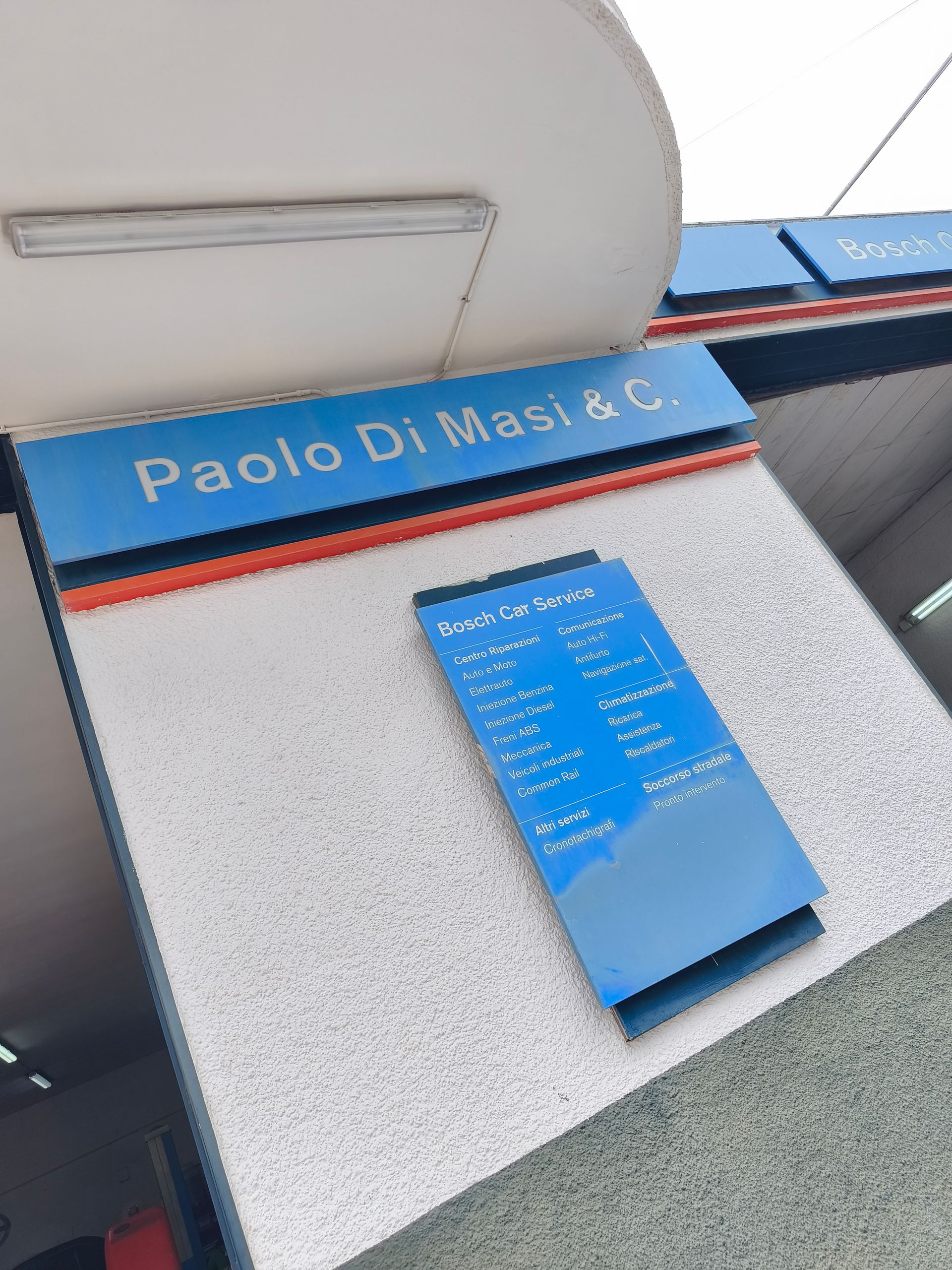 Targa informativa blu su una parete ruvida, sotto un'insegna con la scritta