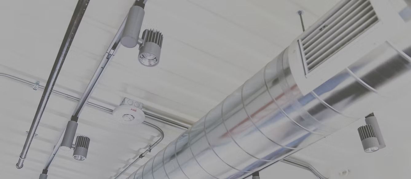 Hands holding a square ceiling vent cover being installed on a white wall