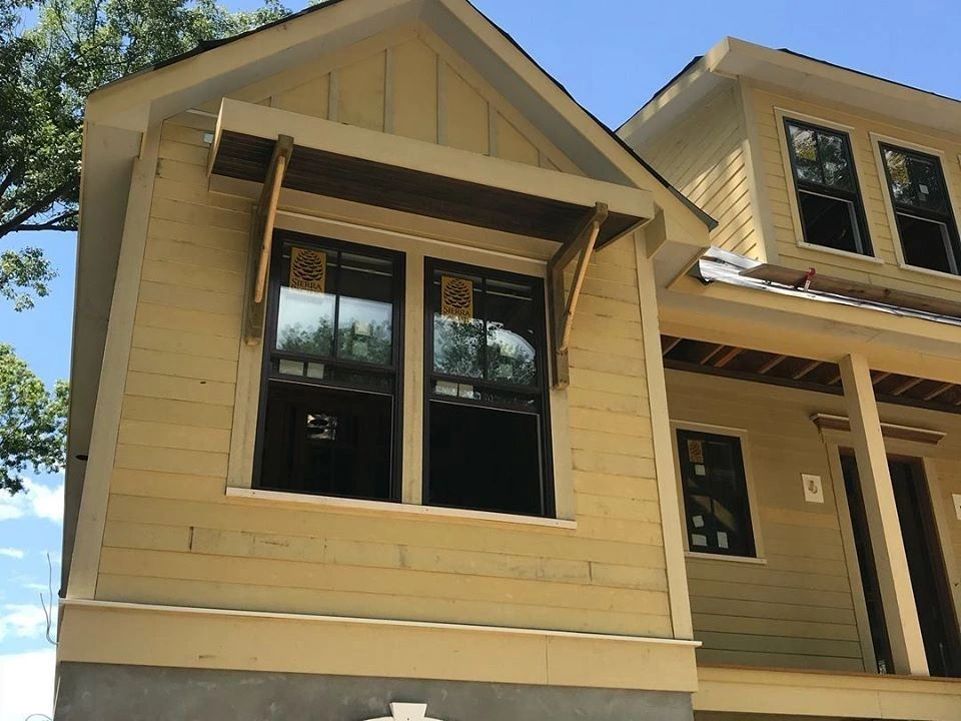 A yellow house with black windows is under construction