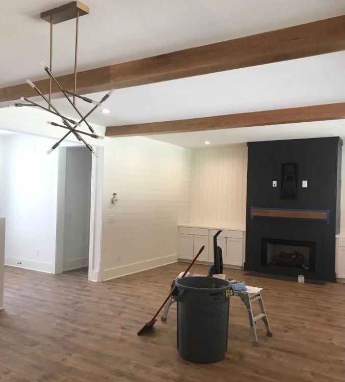 A living room with a fireplace and a trash can on the floor