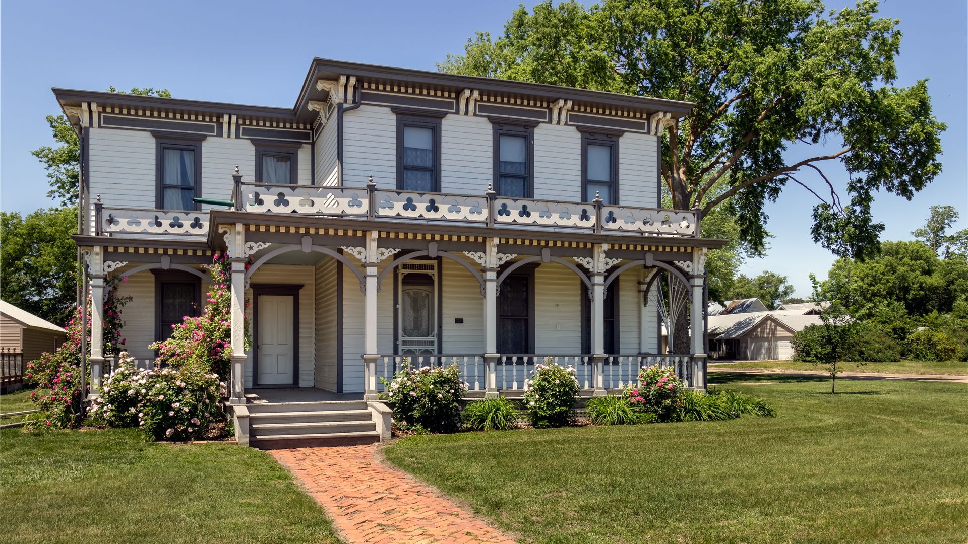 Historic two-story Victorian house with white trim and a front porch on a grassy lawn