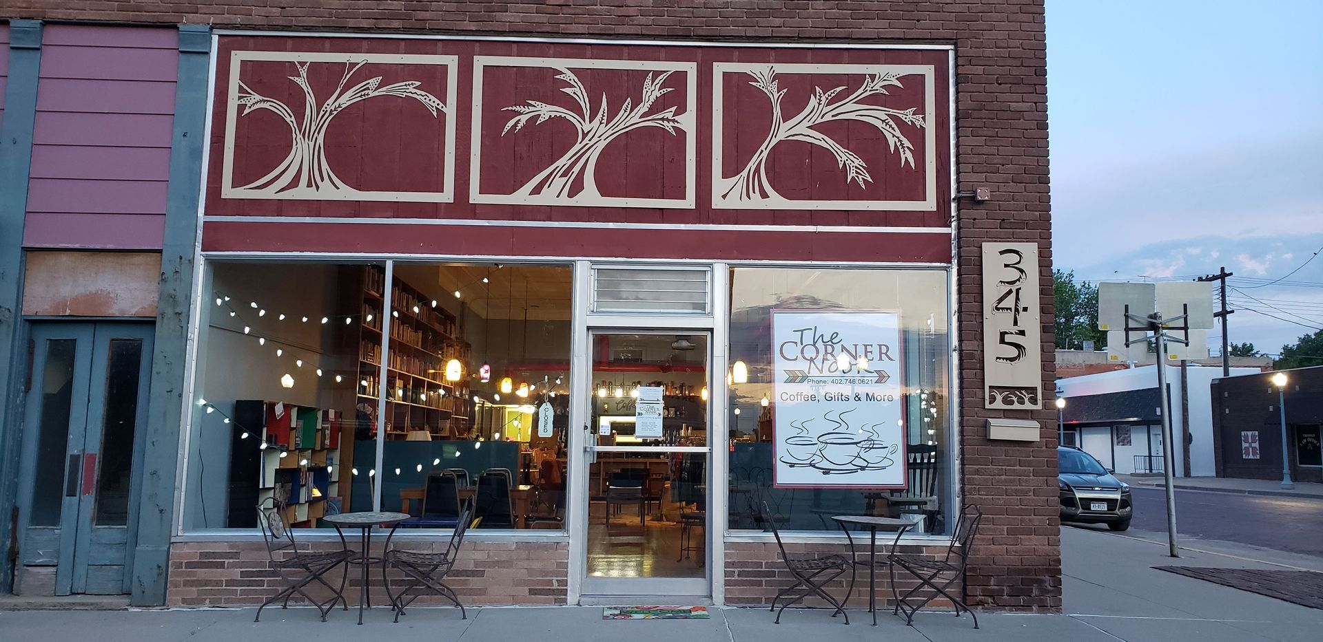 Storefront with tree art above the windows, awning, chairs, and address 345.