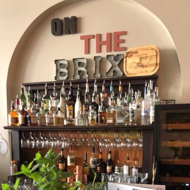 Bar with bottles of liquor and wine glasses; sign 