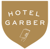 Hotel Garber logo in a gold shield; white text and hand holding papers.