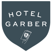 Hotel Garber logo: dark teal shield with white text and a hand holding a stack of cards.