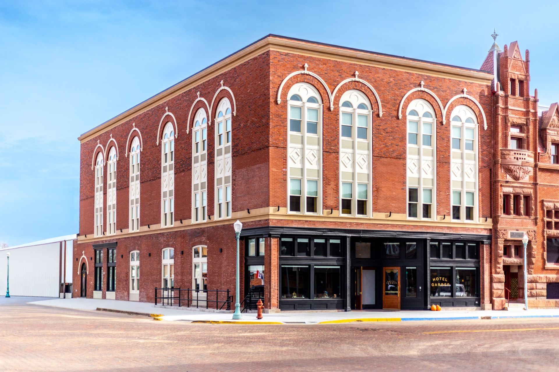 Red brick corner building with arched windows and a black storefront on a quiet street corner