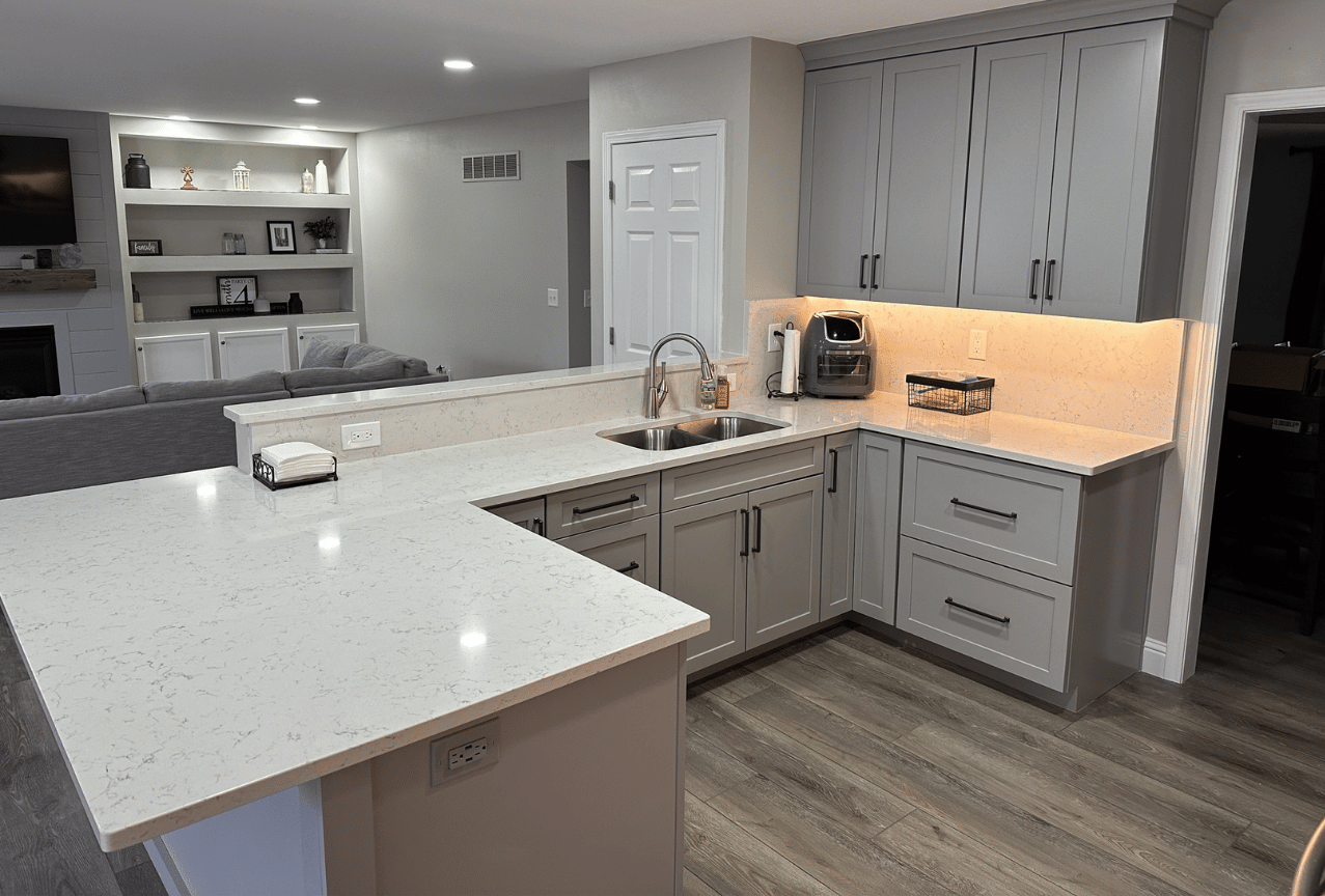 Modern kitchen with white countertops, gray cabinets, island, and warm under-cabinet lighting