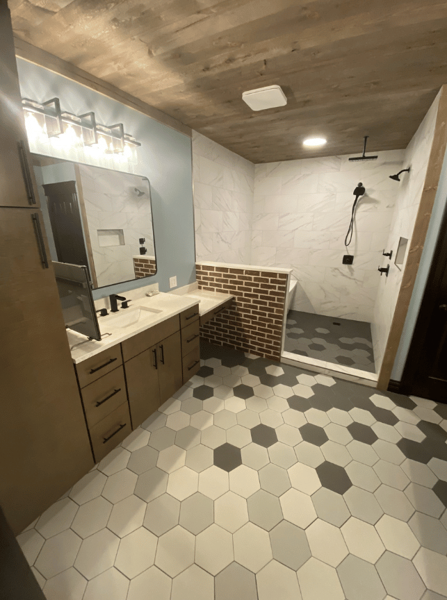 Modern bathroom with hex tile floor, wood vanity, wall mirror, and walk-in shower.