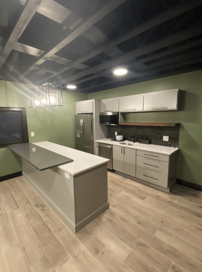 Modern kitchen with gray cabinets, central island, wood floors, and dark exposed-beam ceiling