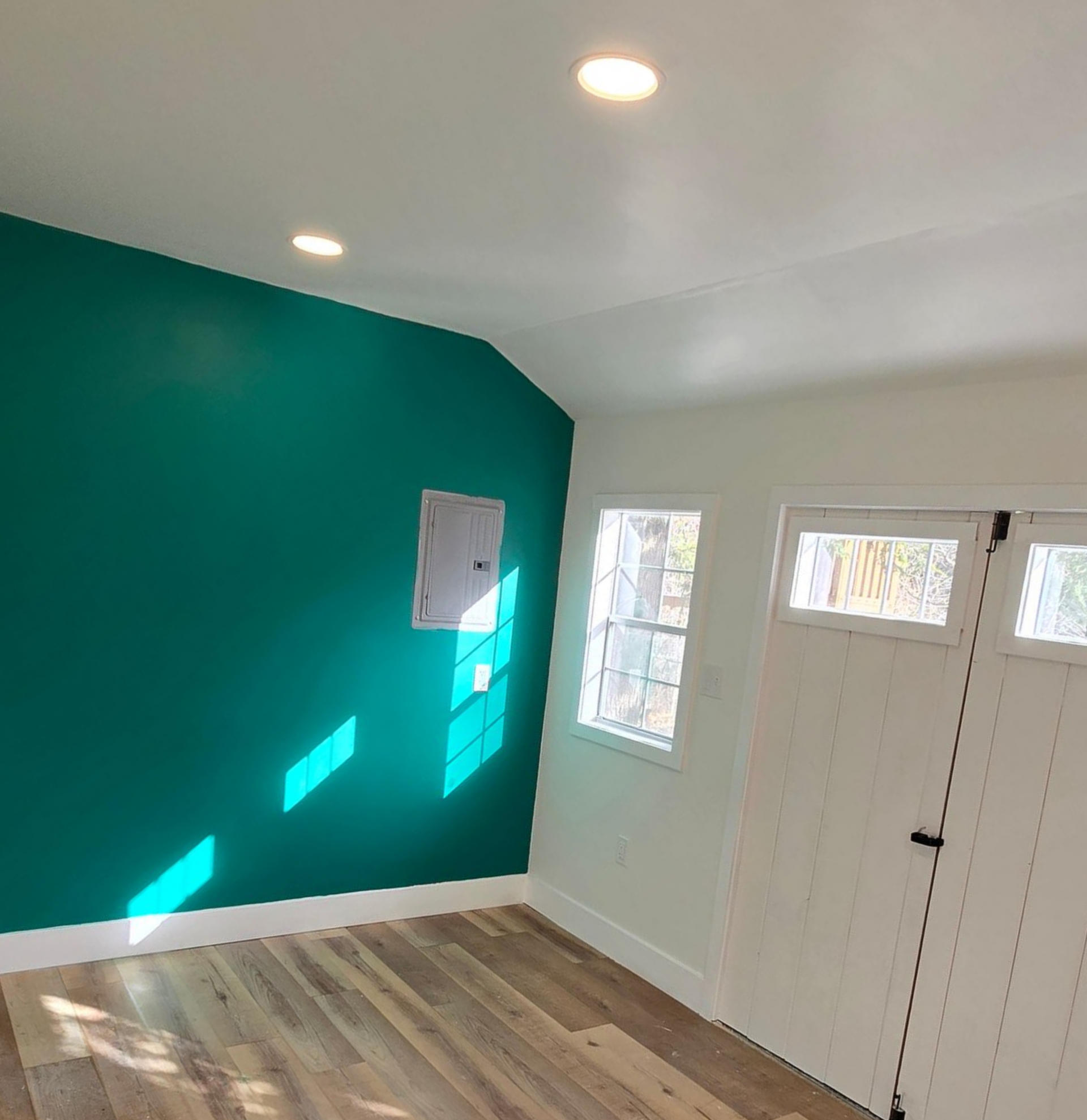 A basement laundry area with a washing machine, utility sink, and clothes dryer on a concrete floor beneath exposed beams.