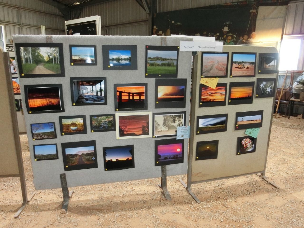 Display of many framed landscape photos arranged on panels in an indoor gallery or workshop.