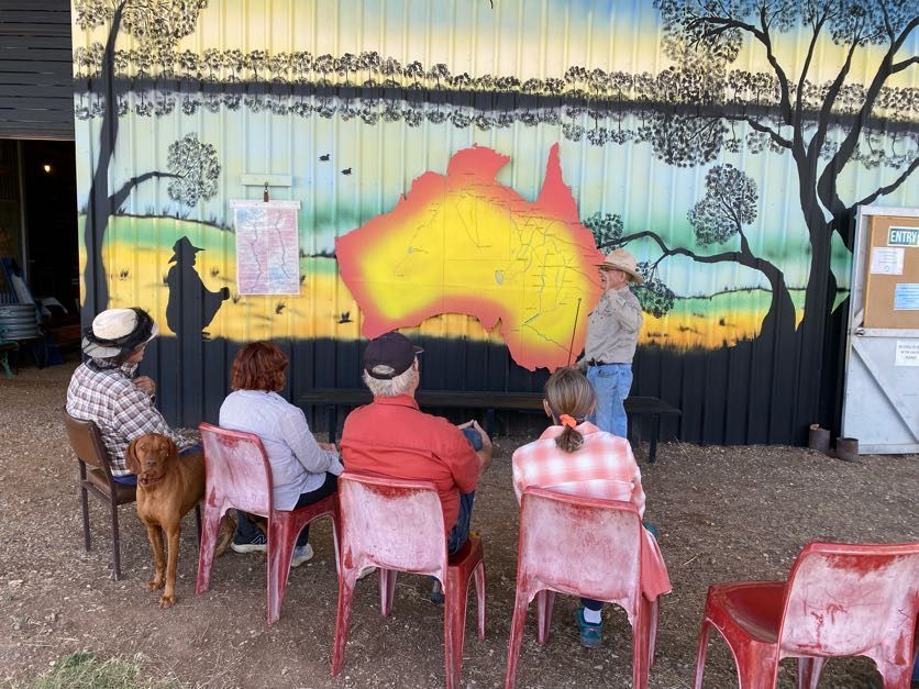 Audience seated outdoors watching a colorful mural painting demonstration