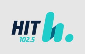 HIT 102.5 radio logo in navy and teal with stylized “h” and dot on a light gray background
