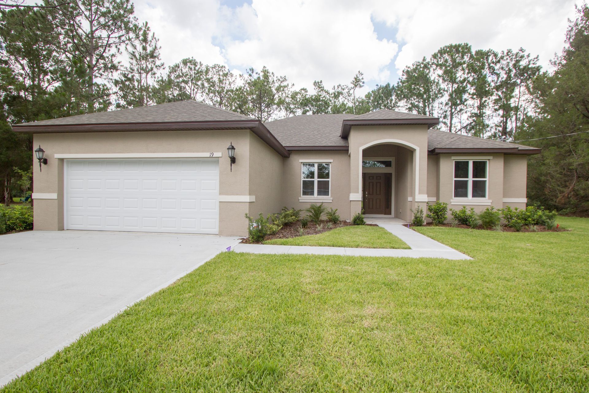 Single-story suburban house with a two-car garage, front lawn, and curved walkway