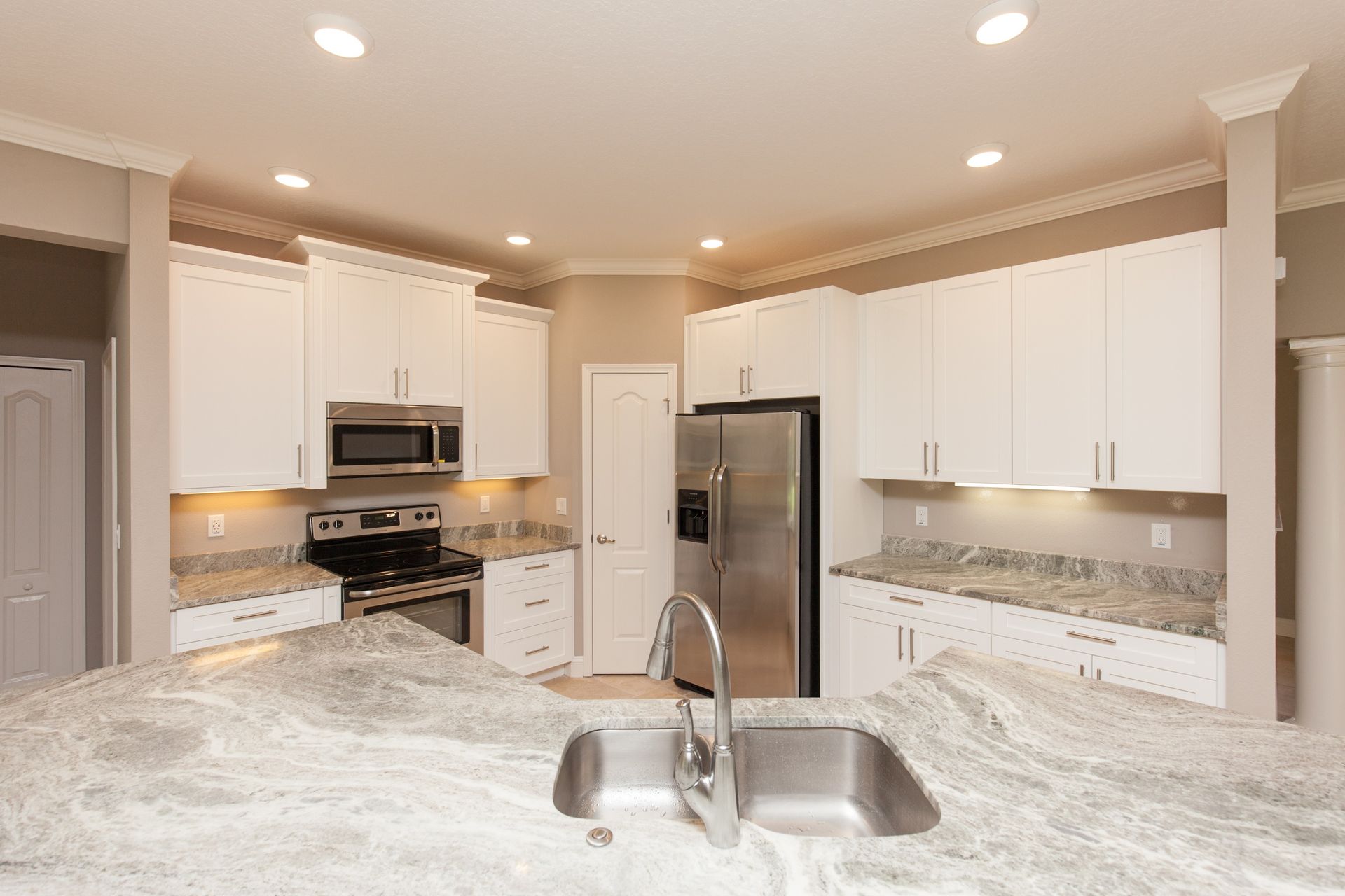 Bright modern kitchen with white cabinets, stainless steel appliances, and a marble island sink