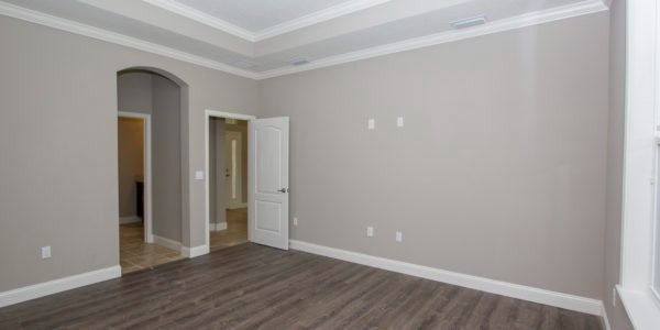 Empty room with gray walls, white trim, dark wood floors, and an open doorway