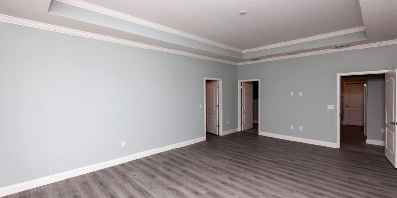 Empty gray living room with wood-look floors and open doorways