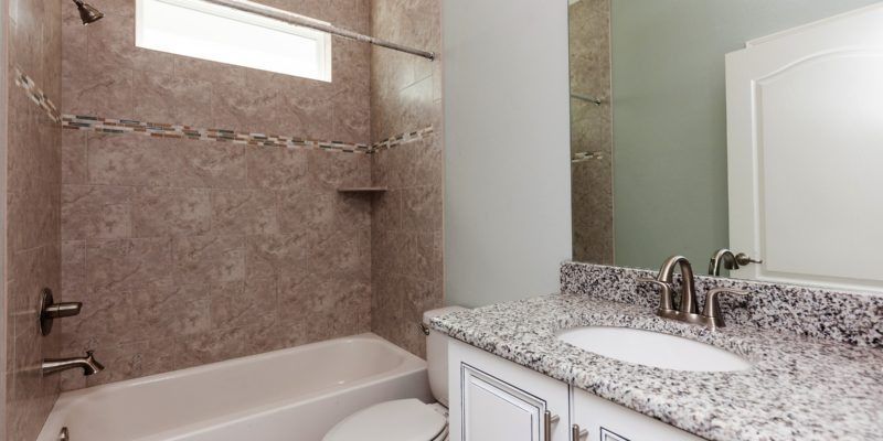 Modern bathroom with tub, granite vanity, and large mirror in beige and white tones