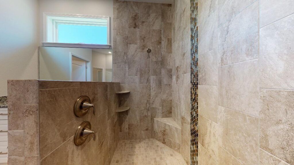 Modern tiled shower with chrome fixtures and frosted window above.