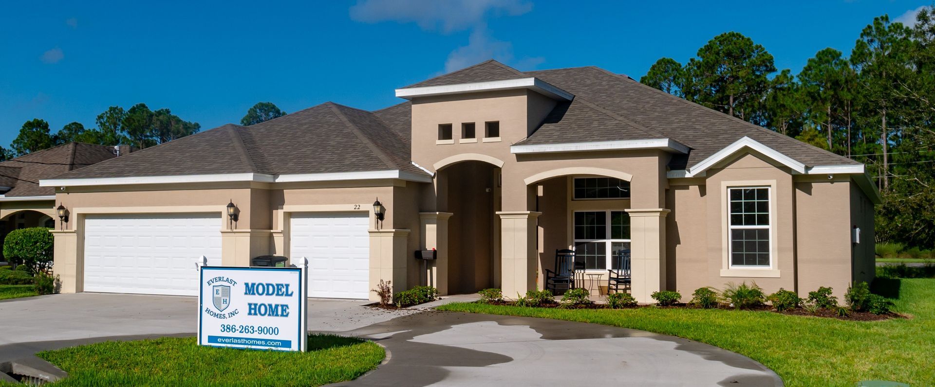 Single-story suburban house with a front porch and real estate sign on a sunny day