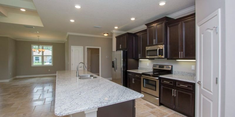 Modern kitchen with large island, dark cabinets, stainless appliances, and recessed lighting