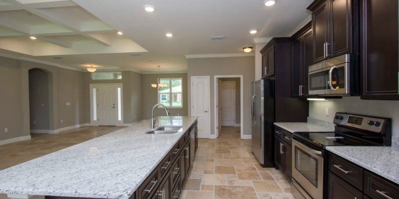 Modern kitchen with long island, dark wood cabinets, granite counters, and recessed lighting
