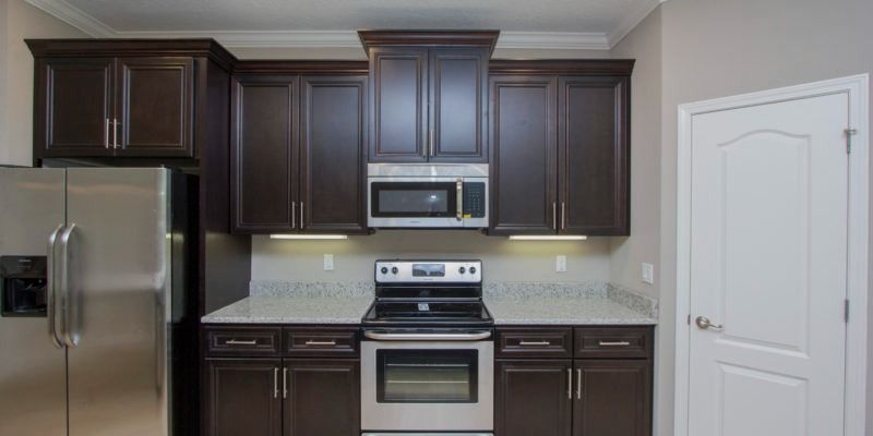 Modern kitchen with dark wood cabinets, stainless steel appliances, and a white door