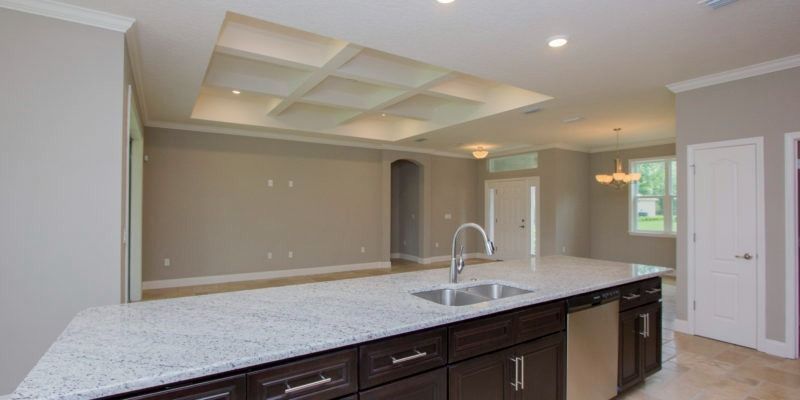 Spacious modern kitchen with a large marble island, pendant lights, and beige walls