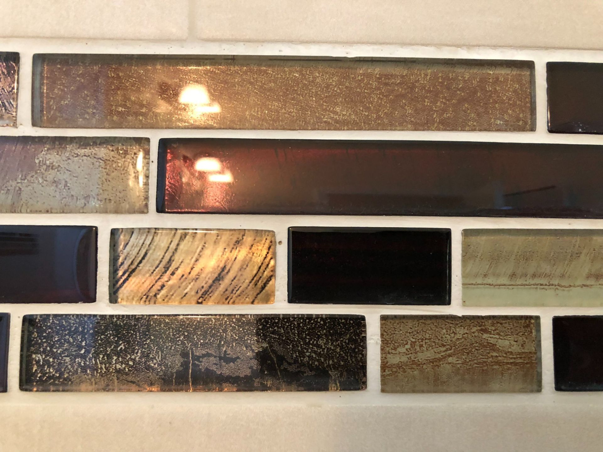 Close-up of a decorative brick wall with textured tan, brown, black, and white tiles