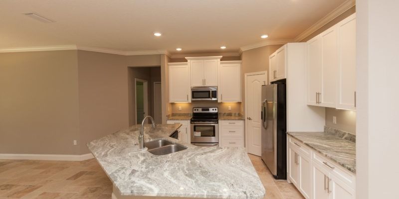 Modern kitchen with white cabinets, stainless appliances, and a large gray-and-white island countertop.