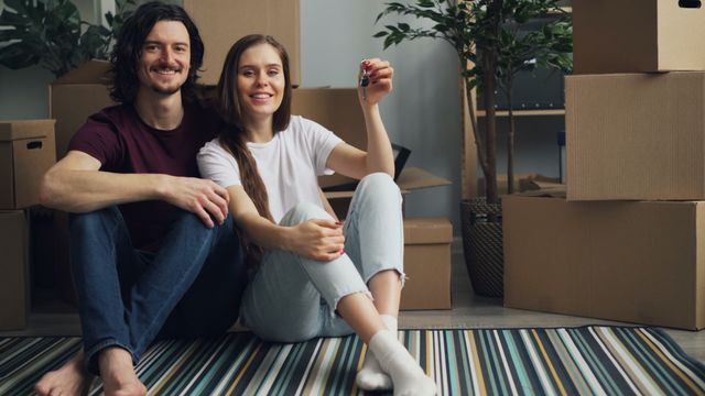 a couple moving into a new home carrying boxes and artwork