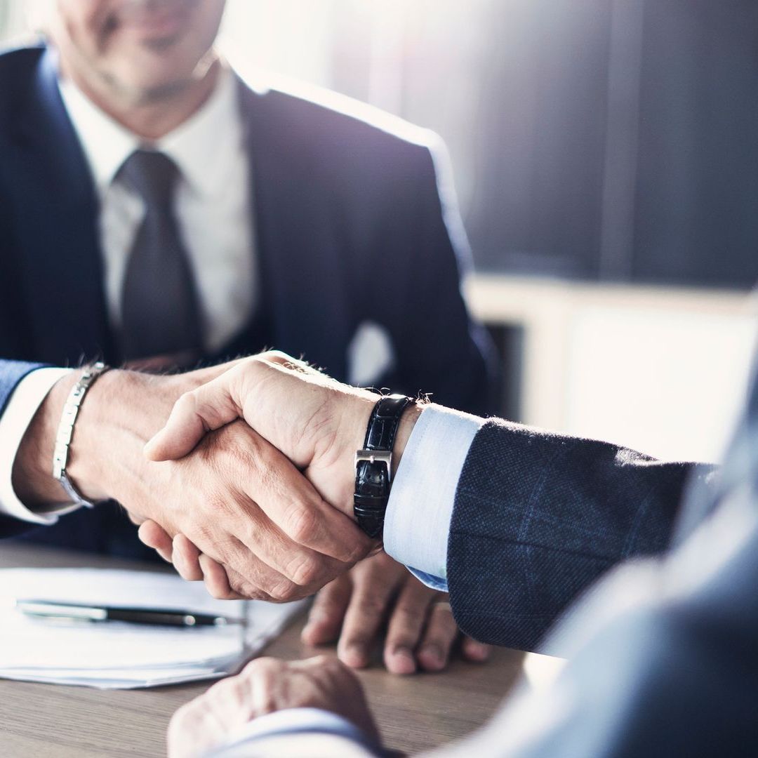 A man in a suit and tie is shaking hands with another man.