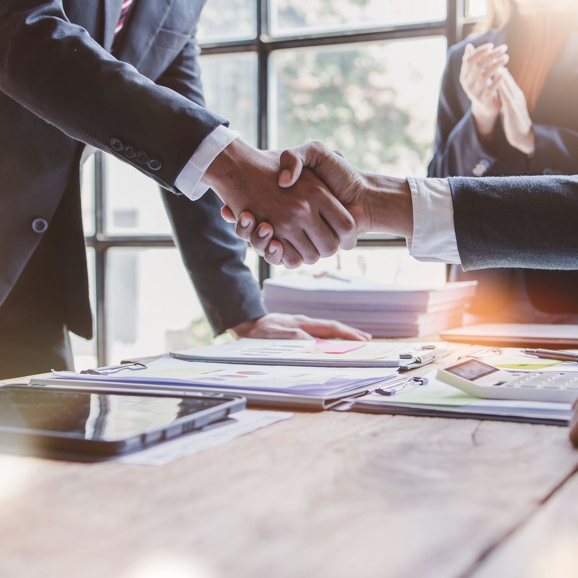 A man and a woman are shaking hands over a table.