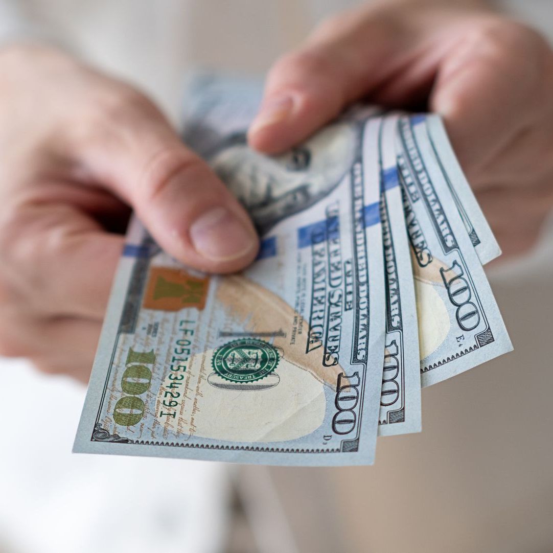 A person is holding a bunch of money in their hands.