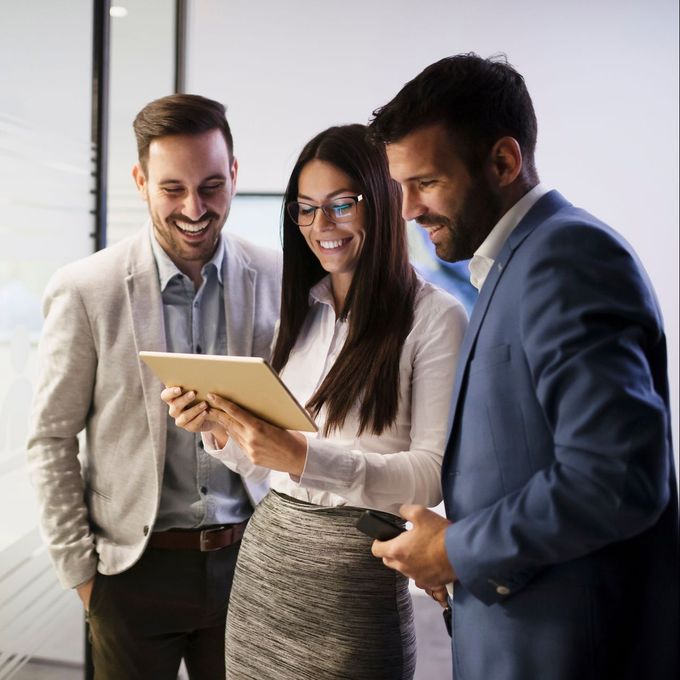 Two men and a woman are looking at a tablet together