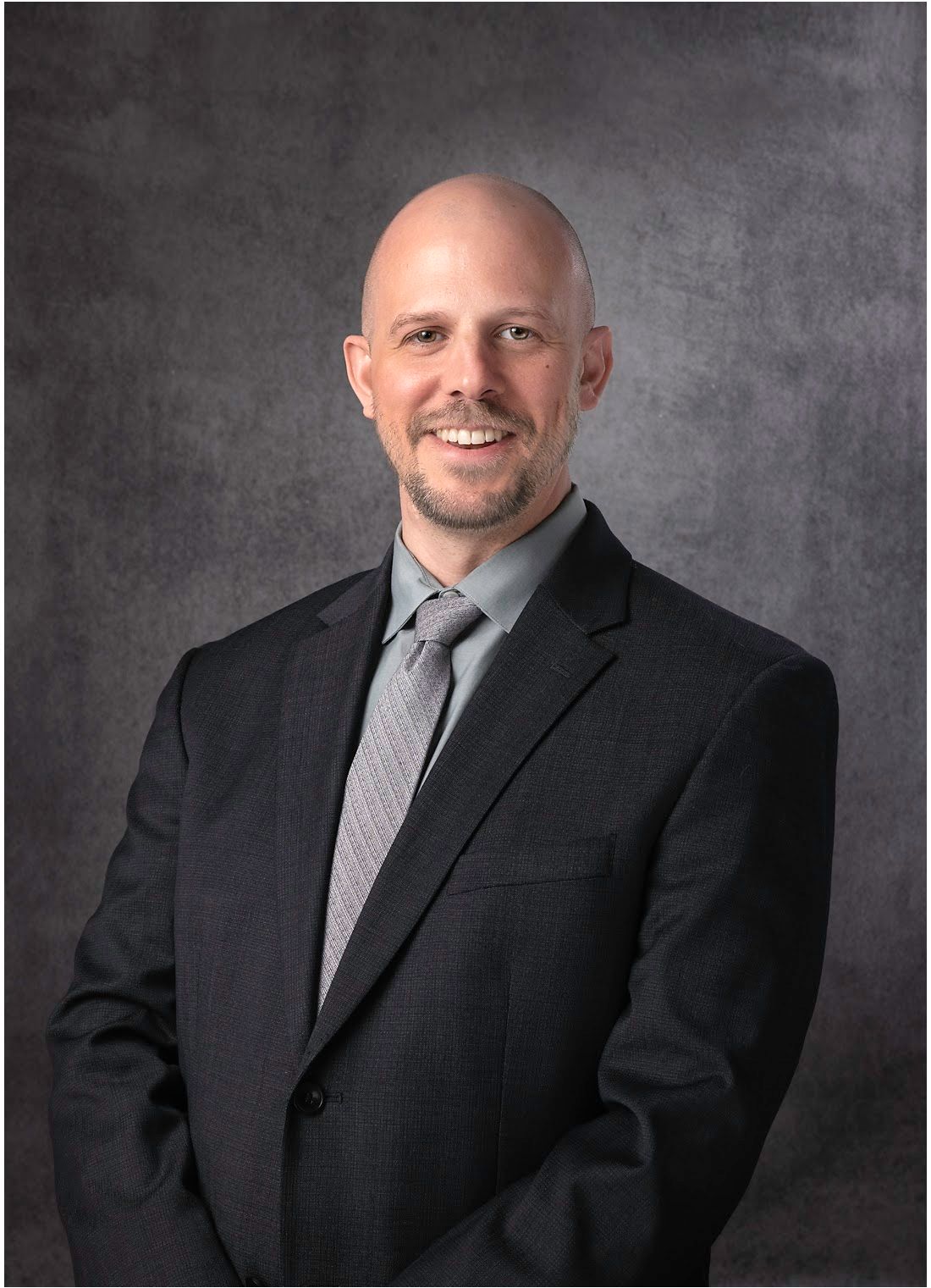 A man in a suit and tie is smiling for the camera
